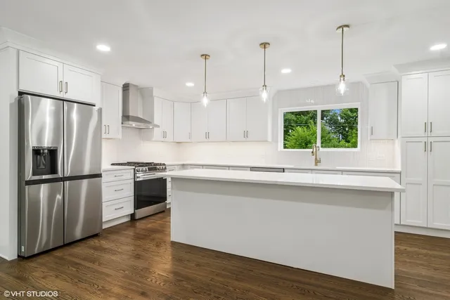 a kitchen with stainless steel appliances granite countertop a refrigerator a sink a stove a microwave and wooden floors