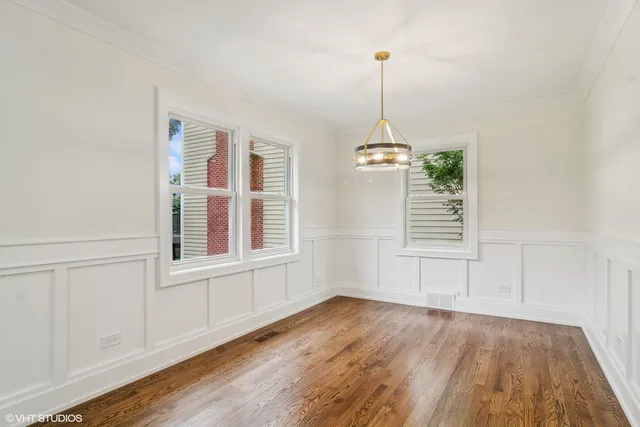 an empty room with wooden floor exposed radiator and windows