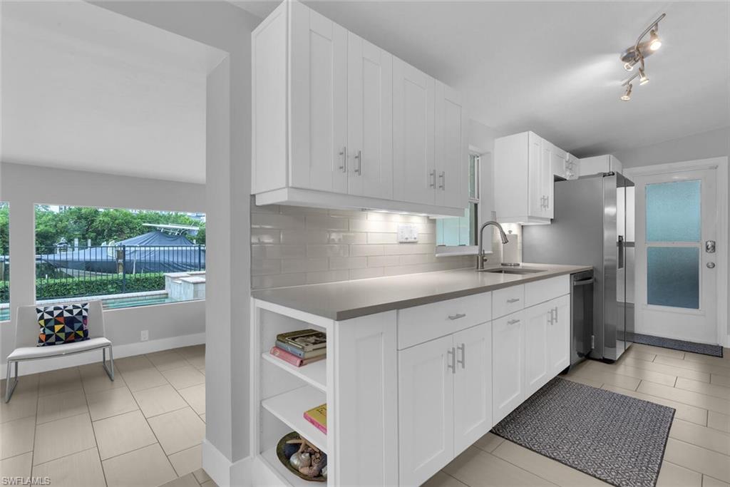 2048 Harbor Lane Naples, FL 34104 - Photo 8 of 35 a kitchen with a sink dishwasher and white cabinets next to a window