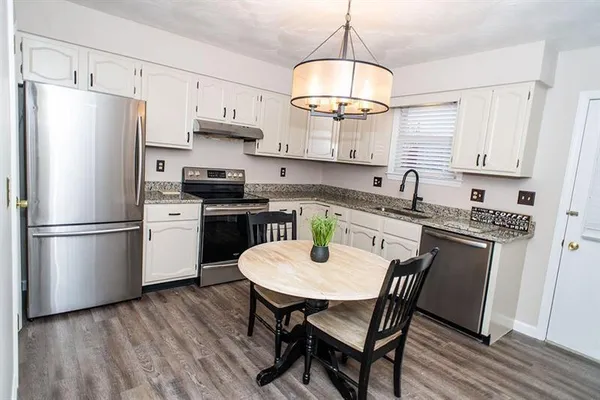 a kitchen with stainless steel appliances a dining table chairs stove refrigerator and cabinets
