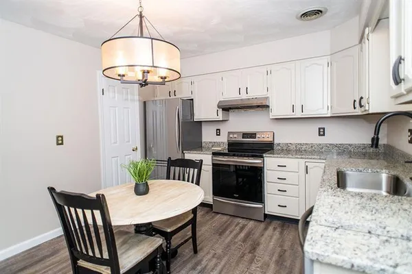 a kitchen with stainless steel appliances kitchen island granite countertop a table chairs and a refrigerator
