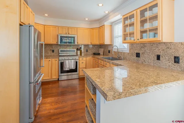 a kitchen with stainless steel appliances granite countertop a refrigerator a sink a stove and oven