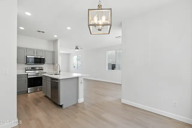 a kitchen with stainless steel appliances a white refrigerator a stove top oven a sink and dishwasher