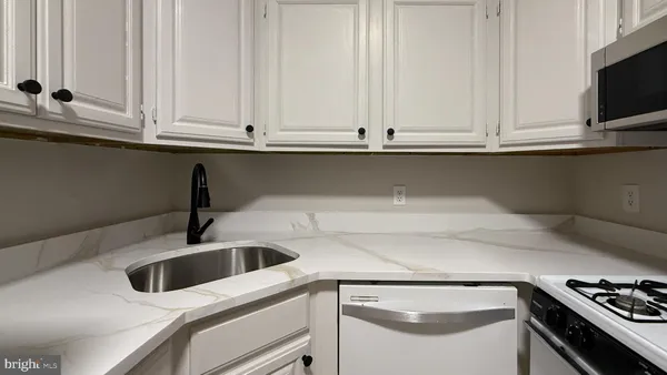 a kitchen with white cabinets and sink