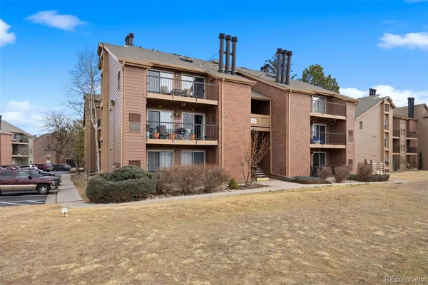 a front view of a building with cars parked