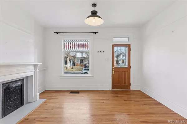 a view of an empty room with wooden floor fireplace and a window