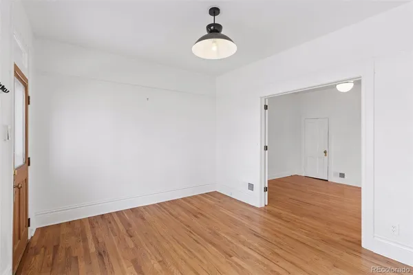 a view of an empty room with wooden floor and a window