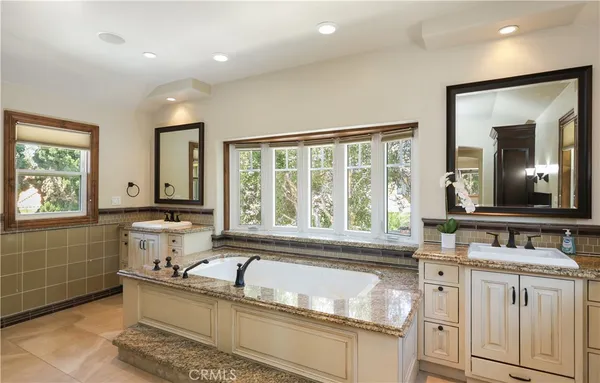 a bathroom with a granite countertop sink mirror and a large window