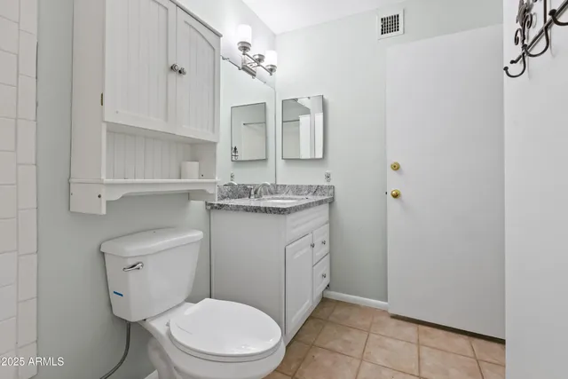 a bathroom with a granite countertop toilet sink and mirror