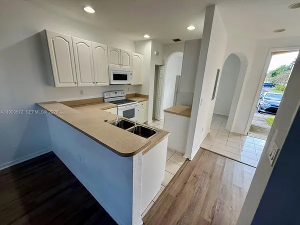 a kitchen with white cabinets and refrigerator