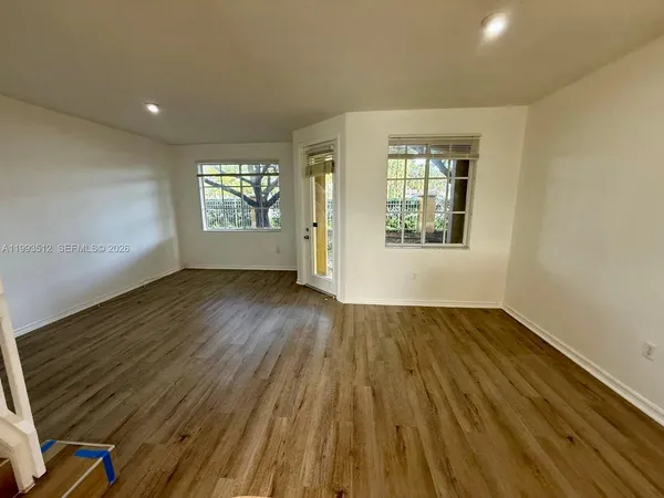 an empty room with wooden floor and windows