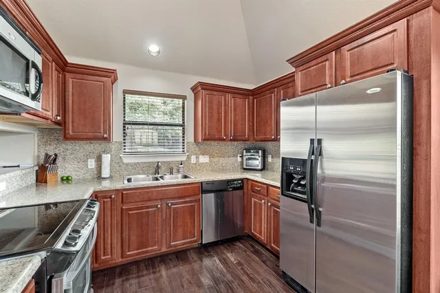 a kitchen with stainless steel appliances a sink cabinets and a window