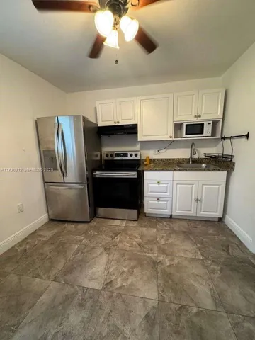 a kitchen with stainless steel appliances granite countertop a stove top oven a sink and a refrigerator