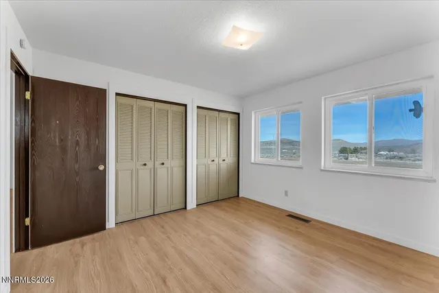 a view of an empty room with window and wooden floor
