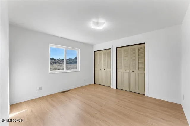 a view of an empty room with window and wooden floor