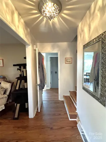 a view of a hallway with a livingroom and wooden floor