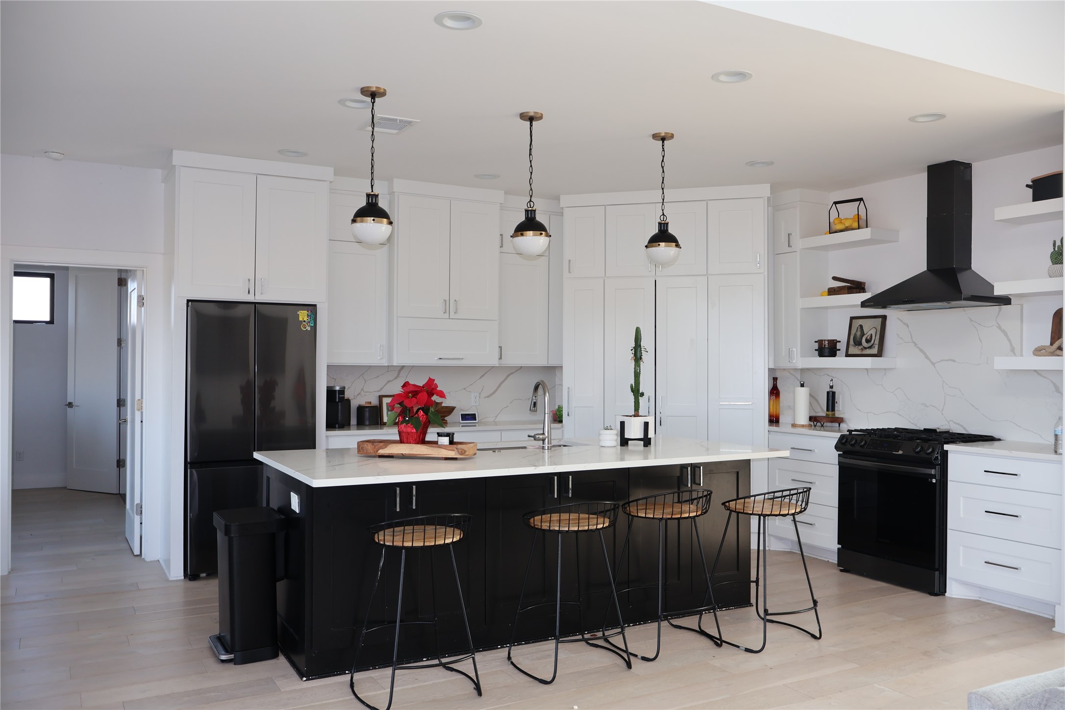 17216 Lund - Carlson Road Elgin, TX 78621 - Photo 4 of 17 Kitchen featuring dark cabinetry, black appliances, wall chimney exhaust hood, a breakfast bar, and white cabinetry