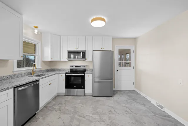 a kitchen with stainless steel appliances granite countertop white cabinets and stove