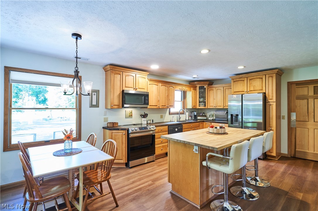 1121 Novak Road Grafton, OH 44044 - Photo 16 of 37 Kitchen with hanging light fixtures, butcher block counters, a center island, wood-type flooring, and appliances with stainless steel finishes