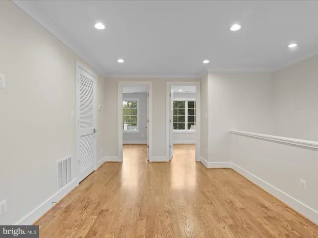 a view of an empty room with wooden floor and windows