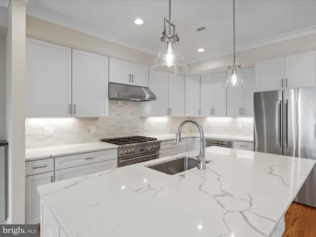 a kitchen with stainless steel appliances granite countertop a sink a stove a refrigerator and cabinets