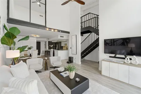 a living room with furniture a flat screen tv and a potted plant