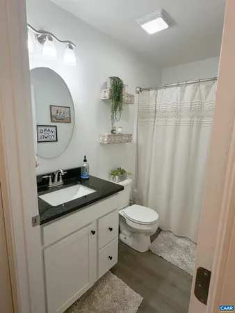 a bathroom with a granite countertop sink a toilet and a mirror