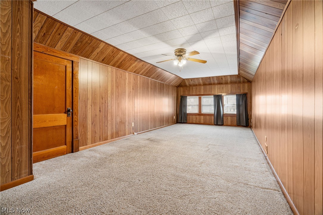 1640 Old Delaware Road Mount Vernon, OH 43050 - Photo 31 of 49 Empty room featuring wooden walls, carpet floors, ceiling fan, and vaulted ceiling