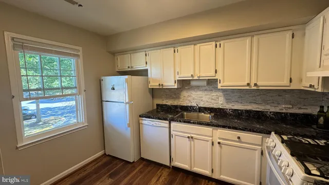 a kitchen with granite countertop white cabinets and white appliances