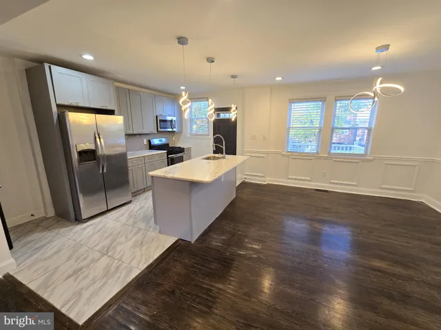a large room with kitchen island a sink wooden floor and a glass door shower