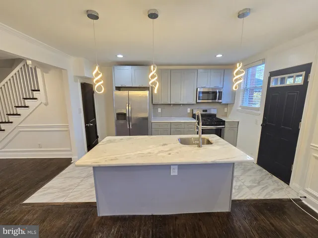 a large kitchen with stainless steel appliances kitchen island granite countertop a refrigerator a sink dishwasher and a stove with wooden floor