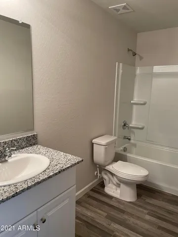 a bathroom with a granite countertop toilet a sink and a mirror