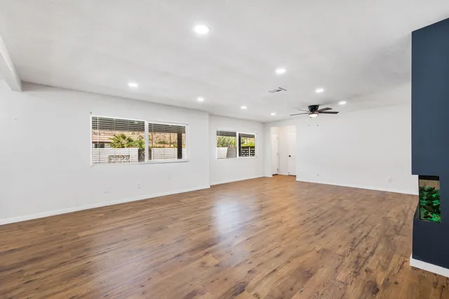 an empty room with wooden floor and ceiling fan