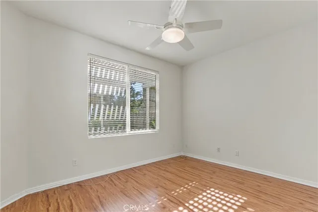 an empty room with wooden floor fan and windows