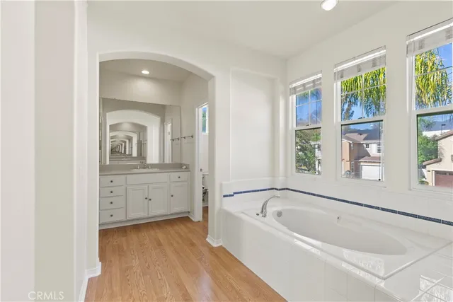 a spacious bathroom with a tub sink and mirror