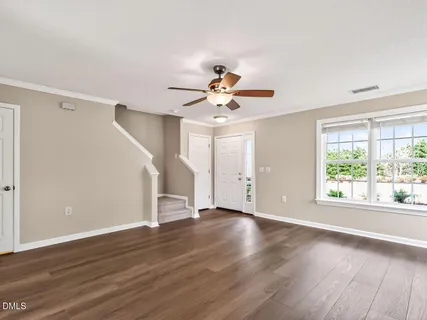 a view of an empty room with wooden floor and a window