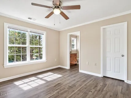 an empty room with wooden floor chandelier fan and windows