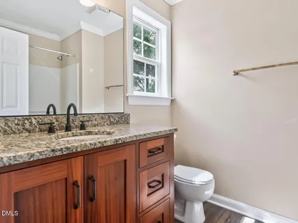 a bathroom with a granite countertop toilet sink and mirror
