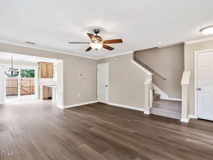 a view of an empty room with wooden floor and a ceiling fan