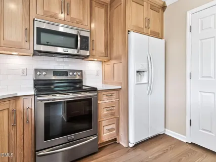 a kitchen with stainless steel appliances granite countertop white cabinets a microwave oven and a refrigerator with wooden floor