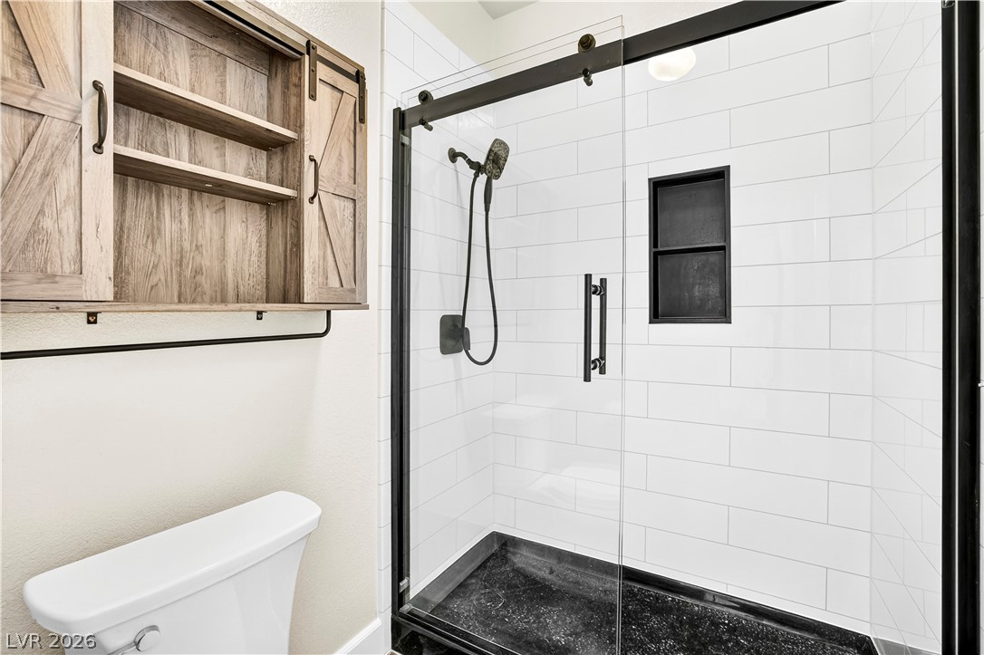 1135 Calico Ridge Drive Henderson, NV 89011 - Photo 25 of 86 A sleek, contemporary walk-in shower features subway tile and a dark-framed glass enclosure.
