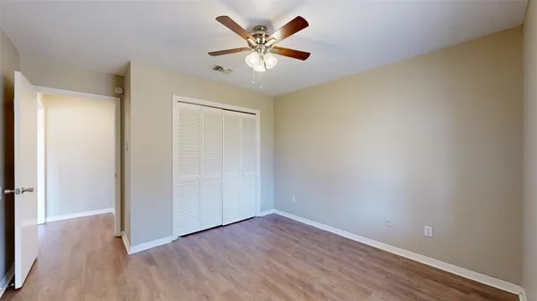 an empty room with wooden floor and a ceiling fan
