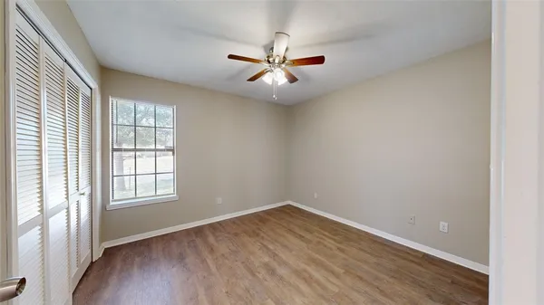 an empty room with wooden floor and ceiling fan