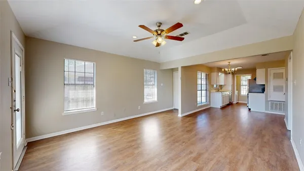 a view of an empty room with window and wooden floor
