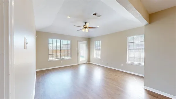 a view of an empty room with a window and wooden floor