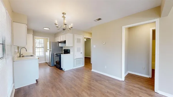 a view of a kitchen with a sink refrigerator and wooden floor