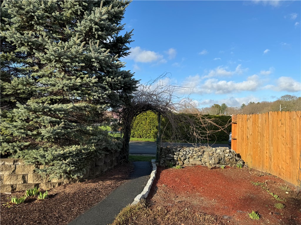 Arbor leads to the side of the property where there is a garage and additional parking.