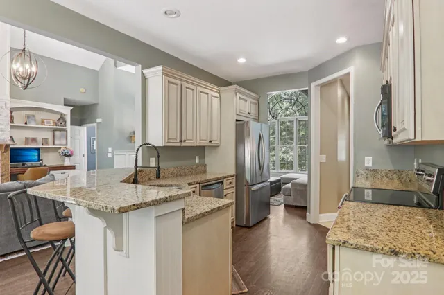 a kitchen with stainless steel appliances granite countertop a sink refrigerator stove and microwave