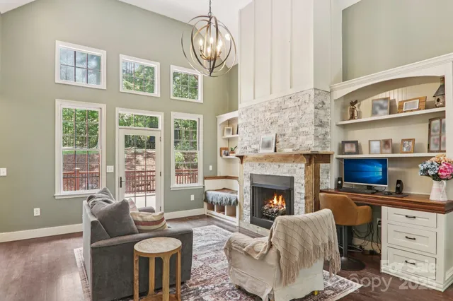 a living room with furniture a fireplace a flat screen tv and windows