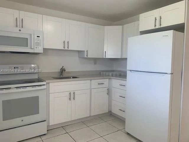 a kitchen with white cabinets and white appliances